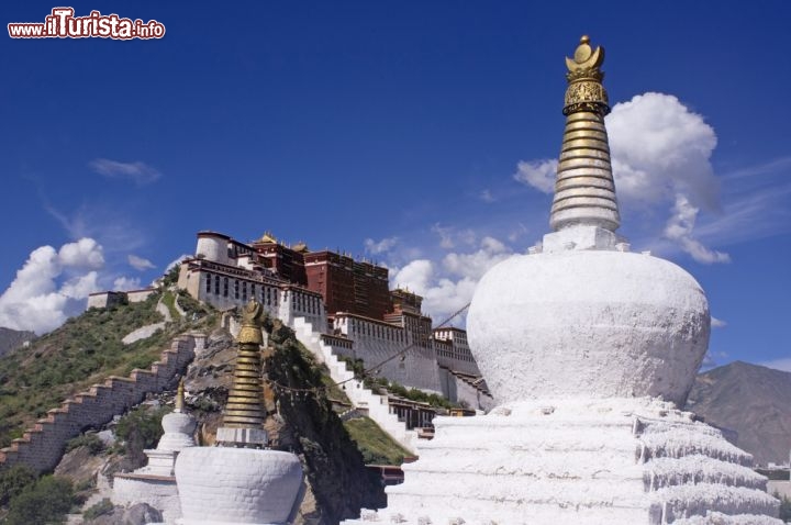 Immagine Architetture tibetane in primo piano, mentre  in lontananza si vede il profilo inconfondibile del Potala Palace di Lhasa, l'edificio più celebre del Tibet, la regione della Cina - © cl2004lhy / Shutterstock.com