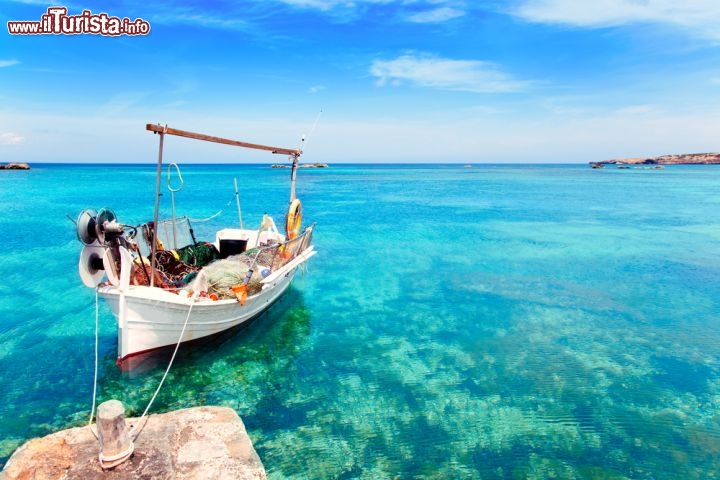 Immagine Una barca di pescatori a Formentera, al largo della spiaggia di Es Pujols, una delle più vivaci e scatenate dell'isola. Di giorno ci si gode l'acqua turchese e trasparentissima, ma al calar del sole comincia la movida nei locali all'aperto e nelle discoteche - © holbox / Shutterstock.com