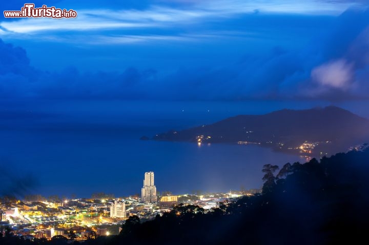 Immagine La baia di Phuket by night è ancora più bella: la città illuminata è un gioiello, su una coperta blu fatta di mare e di cielo - © Jiggo_thekop / Shutterstock.com