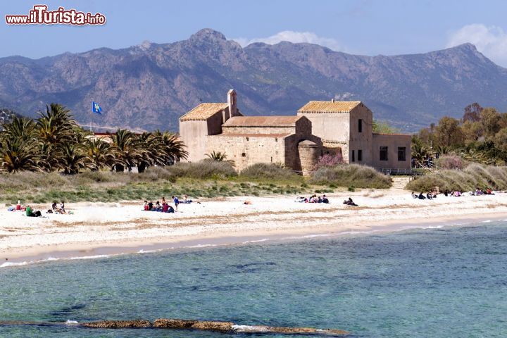 Immagine La spiaggia del sito archeologico di Nora e la chiesa di Sant'Efisio: in questi luoghi, nei dintorni di Pula, nel 303 dopo Cristo il Santo venne martirizzato sotto l'impero di Diocleziano - © Tramont_ana / Shutterstock.com