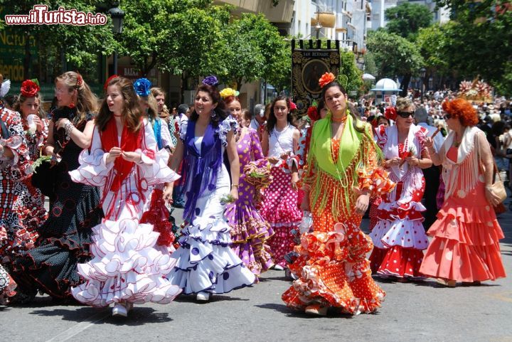 Immagine Donne in festa passeggiano lungo la strada con indosso i tradizionali abiti da flamenco durante la festa Romeria San Bernabe a Marbella, Spagna.  - © Arena Photo UK / Shutterstock.com