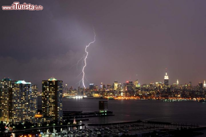 Immagine Skyline notturna di Manhattan a New York, Stati Uniti. Una suggestiva immagine by night della skyline di Mahnattan fotografata con un fulmine sullo sfondo - © Qing Ding  / Shutterstock.com