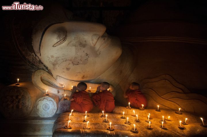 Immagine Giovani monaci buddhisti pregano in un tempio di Bagan, Myanmar. Con la luce delle candele tre giovani religiosi del sudest asiatico pregano in un luogo di culto della città di Bagan - © Ekkachai / Shutterstock.com