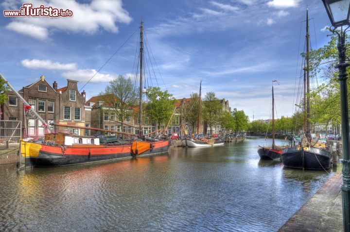 Immagine Paesaggio cittadino a Schiedam, Olanda. L'azzurro del cielo limpido si riflette nelle acque del canale dove sono ormeggiate le tradizionali barche.