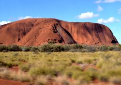 La montagna sacra di Uluru fotografata in corsa dal pulmino - Il magnifici colori di Ayers Rock si fondono con quelli del bush, la bassa vegetazione tipica dell'outback australiano, e con ...