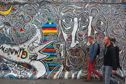 Turisti visitano la East Side Gallery: una parte del muro di Berlino ricoperta da apere di più di 100 artisti dal 1990. - © Tupungato / Shutterstock.com