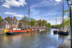Paesaggio cittadino a Schiedam, Olanda. L'azzurro del cielo limpido si riflette nelle acque del canale dove sono ormeggiate le tradizionali barche.
