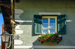Particolare di una casa residenziale a Gmuend in Kaernten, distretto di Spittal an der Drau: una finestra con persiane in legno e fiori colorati.

