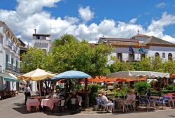 Turisti in relax ai caffé in Plaza de los Naranjos a Marbella, Spagna. Circondata da tipiche case andaluse bianche e da edifici storici, questa bella piazza ospita al suo centro una fontana ...