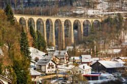 Il ponte della ferrovia incombe sulle case del borgo di Saint-Ursanne in Svizzera, imbiancato dopo una nevicata invernale - © SilvanBachmann / Shutterstock.com
