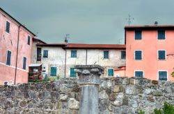 Resti di un'antica colonna nel centro di Brugnato, La Spezia, Italia. Sullo sfondo le abitazioni dalle facciate color pastello della cittadina.
