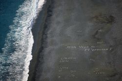 Utilizzando dei sassi bianchi, locali e turisti lasciano delle scritte sulla spiaggia nera di Nonza, che sono visibili dai punti panoramici sopra la spiaggia della Corsica