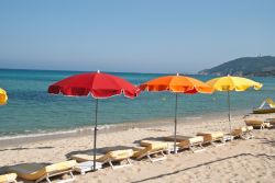 Sdraio e ombrelloni colorati su una spiaggia sabbiosa a Saint-Tropez, Costa Azzurra (Francia).

