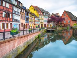 Un pittoresco scorcio del centro di Colmar, Francia: un canale con le tipiche abitazioni colorate e dall'architettura a graticcio - © StevanZZ / Shutterstock.com