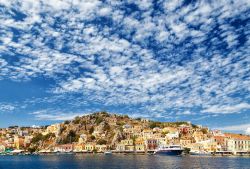 Una barca attraccata al porto dell'isola di Symi, Grecia, con le case sullo sfondo.

