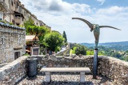 Veduta di una tipica via del villaggio con statua lungo le mura fortificate, Saint-Paul-de-Vence, Francia. Da sempre questa località è stata fra le predilette di artisti, poeti ...