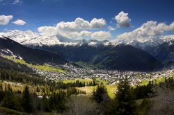 Verbier illuminata dal sole sotto un cielo azzurro e con le vette ricoperte di neve a fare da cornice, Svizzera.



