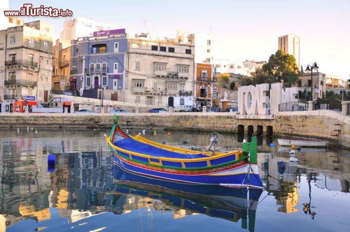 Immagine Le acque calme del porto St Julian's: a colorare la scena una barca tipica da pescatore, come se ne vedono molte sull'isola di Malta - © Arseniy Krasnevsky / Shutterstock.com