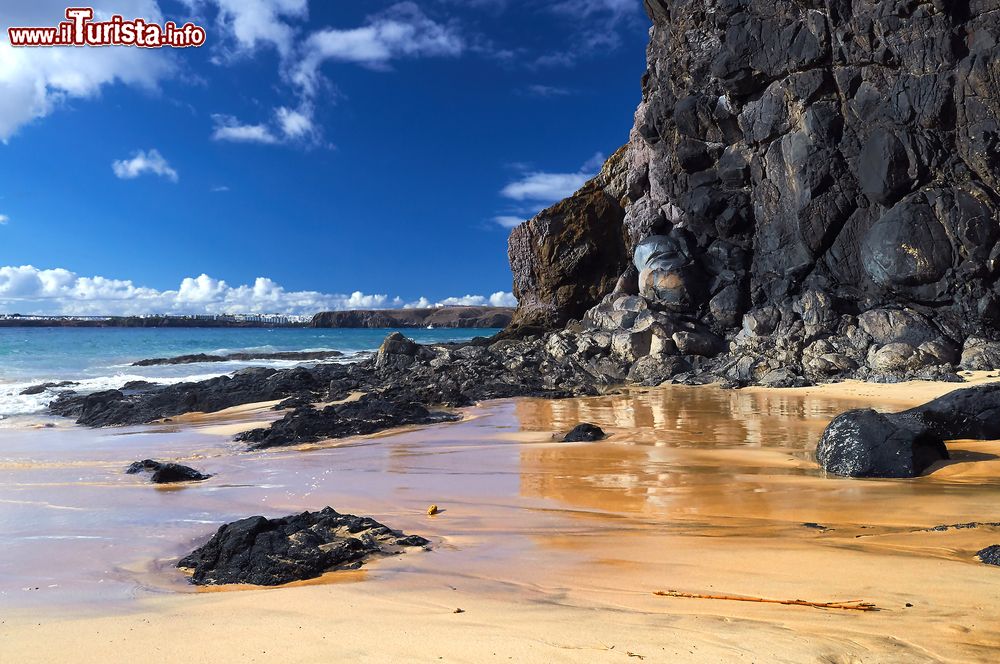 Immagine Spagna: spiaggia presso la località di Playa Blanca, nel sud di Lanzarote (Canarie). Le rocce visibili nella foto sono nere perché di origine vulcanica.