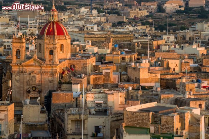 Immagine Veduta aerea di Rabat, la capitale dell'isola di Gozo (Malta) - Conosciuta anche come "Victoria" secondo gli inglesi e come "Rabato del Castello" in italiano, più semplicemente abbreviata in "Rabat" e conosciuta ai più con quest'ultima definizione maltese, la capitale dell'isola di Gozo ha avuto diversi cambiamenti di nome in relazione al fatto che doveva distinguersi dalle omonimie. La particolarità più stucchevole di questa località è data dal fatto che si erge su una rupe completamente e primeggia con tutto il suo splendore su tutta l'isola, sovrastandone gli spazi in maniera ordinata e densa - © Ralf Siemieniec / Shutterstock.com