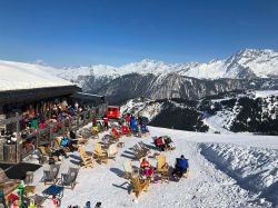Piste da sci nel resort di Courchevel (Francia) con turisti e sciatori al ristorante e in relax al sole - © FrimuFilms / Shutterstock.com