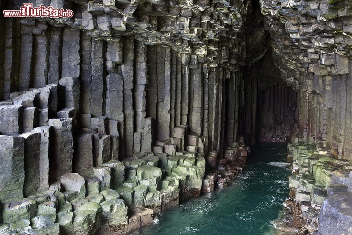 Fingal Cave, isola di Staffa (Ebridi interne) in Scozia - Al largo della più grande Isola di Mull, nel gruppo delle Inner Hebrides, troviamo uno dei luoghi più affascinanti della Scozia: l'isola di Staffa, il cui nome deriva da una parola vikinga. Questo popolo nordico era rimasto colpito dai basalti colonnari di questa isola delle Ebridi, una specie di "palizzata di roccia", formatasi per il raffreddamento di antiche colate di lava. Tra queste colonne di roccia si apre la Fingal's Cave, una grotta marina resa suggestiva dalla cornice di basalti esagonali, che assomigliano ad una distesa di canne d'organo. E, in effetti, l'effetto acustico delle onde, che si frangono all'interno della grotta con echi e rimbombi, è piuttosto suggestivo. Compositori musicali come Felix Mendelssohn e gli stessi Pink Floyd hanno tratto ispirazione da questo luogo, citato anche dallo stesso Jules Verne nel suo libro Il Raggio Verde. Ricordiamo che per vedere dei basalti colonnari così belli , ci si può solo recare al Giant Causeway nell'Irlanda del Nord  - © Steve Allen / Shutterstock.com