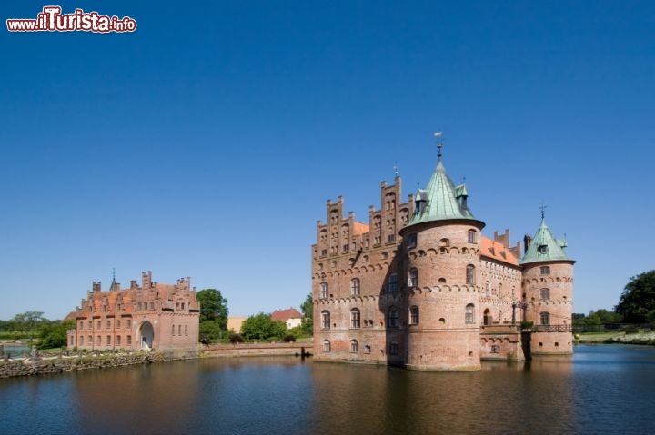 Castello di Egeskov, isola di Fyn, Danimarca - Questa magnifica fortezza del rinascimento (16° secolo) si trova sull'isola di Fionia (Odense), ed è uno dei castelli del periodo, meglio conservati in Europa. Il suo nome, tradotto in italiano, recita testalmente come "foresta di querce", ma non si riferisce alle piante predominanti di questa regione, ma probabilmente alle fondamenta del castello, costituita da una fitta serie di pali in legno. Si tratta di un esempio di Water Castle, cioè una fortezza circondata completamente da uno specchio d'acqua, che ne forniva quindi una maggiore sicurezza. Oltre al lago all'esterno si trova un magnifico Giardino Barocco, con un particolare labirinto di faggi. Gli interni ben conservati, accogliono circa 200.000 visitatori ogni anno, che vengono a vedere anche i vari musei allestiti al suo interno, tra cui il particolare museo della Falck - © MortenElm /  iStockphoto LP.