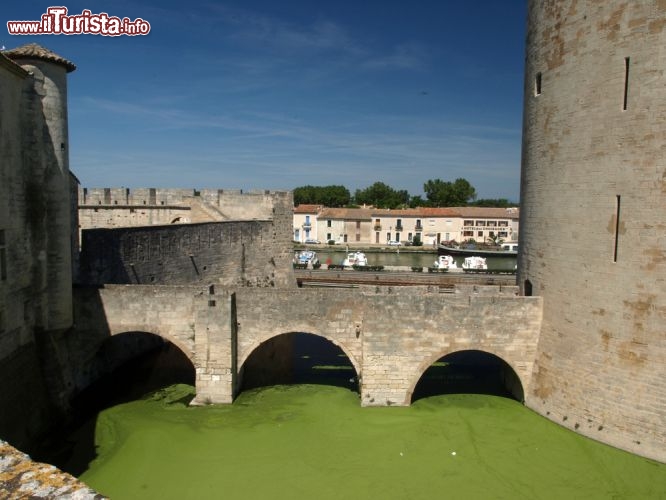 Immagine Borgo e canali di Aigues Mortes, Provenza - Passeggiando lungo il tratto di mura difensive accessibili al pubblico si possono ammirare caratteristici scorci paesaggistici come quello ritratto in questa immagine che permette di ammirare al tempo stesso parte delle fortificazioni e dei canali su cui si affacciano le case degli aiguesmortais, come vengono chiamati gli abitanti della città © wjarek / Shutterstock.com