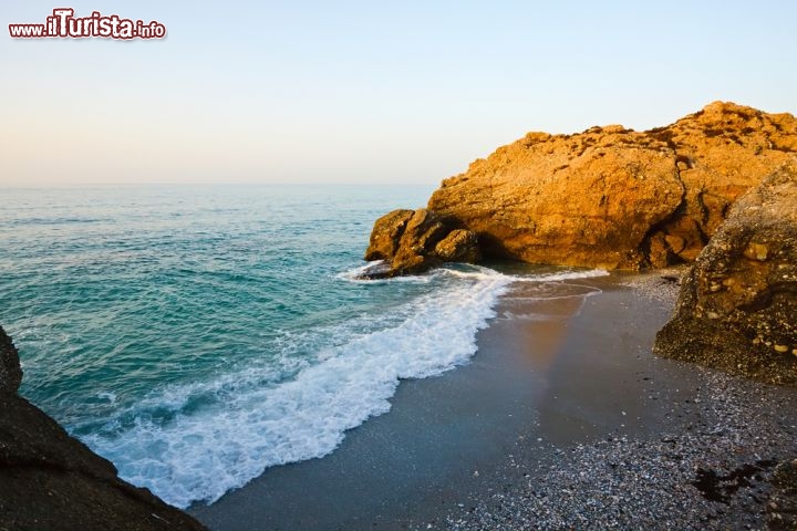 Immagine Alba su una cala a Nerja, Spagna -  Sviluppata intorno ad un piccolo villaggio costiero a cui, grazie al turismo, si sono via via aggiunti quartieri residenziali, questa bella località della Costa del Sol si trova a soli 50 km da Malaga e a poco più di un'ora da Granada. A renderla particolarmente gradita ai turisti sono le sue spiagge con fondo sabbioso e le sue tante calette racchiuse fra scogliere. Al calar del sole, le rocce acquisiscono colori dalle mille sfumature riflettendosi sull'acqua limpida del Mar Mediterraneo © S.Borisov / Shutterstock.com