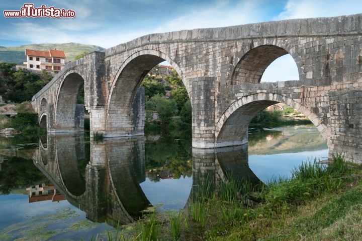 Immagine Antico ponte in pietra a Trebinje, Bosnia Erzegovina - Circondata da pietre bianche e illuminata dal sole del Mediterraneo, Trebinje è considerata una delle ultime oasi del vecchio continente dove il tempo sembra quasi essersi fermato e dove la natura è protagonsita assoluta. Il picco della sua gloria questa città della Bosnia Erzegovina lo raggiunge nel XIII secolo quando nei libri viene descritta come una piccola Venezia per i tanti ponti in pietra che attraversano il fiume Trebisnjica © dinosmichail / Shutterstock.com