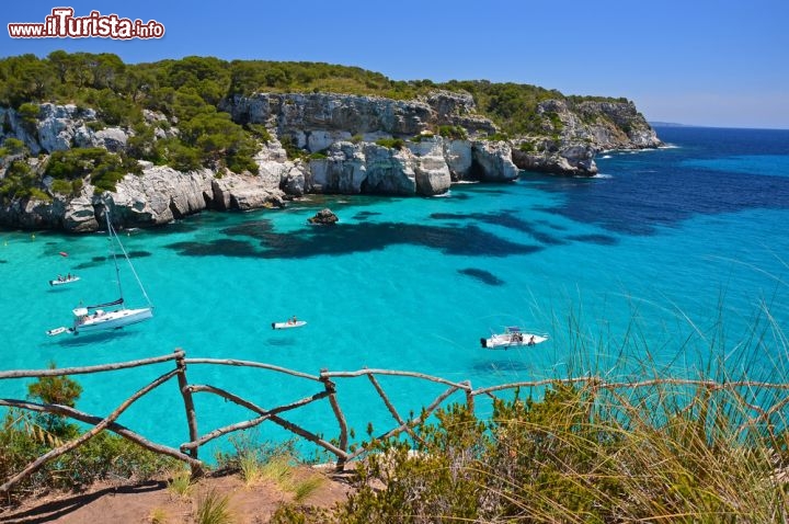 Immagine Cala Macarella, nel nord di Minorca, dista circa 15 km da Ciutadella. Le alte scogliere ombreggiate dalla pineta, la sabbia bianca e l'acqua trasparentissima ne fanno un piccolo paradiso a forma di ferro di cavallo - © Pawel Kazmierczak / Shutterstock.com