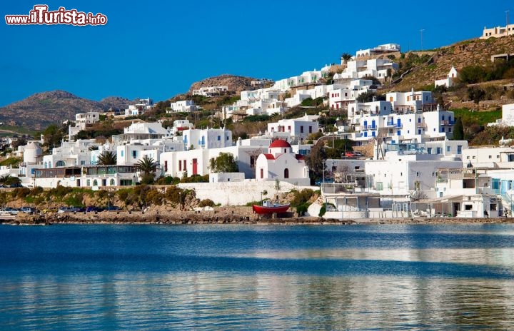 Immagine La baia del vecchio porto di Mykonos in Grecia. Da notare una tipica barca rossa e la chiesa ortodossa dal tetto amaranto. Ci troviamo nell'aripelago delle  Cicladi, nel mare Egeo - © Natalia Dobryanskaya / Shutterstock.com