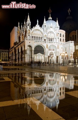 Immagine Basilica San Marco ed acqua alta a Venezia. Piazza San Marco si trova in un basso topografico della città di Venezia, e quindi viene allagata con facilità dalle maree più importanti, se a d esse s'aggiunge una componente meteorologica di vento di scirocco. Con 90 cm di altezza la piazza viene coperta completamente, mentre le maree eccezionali sono quelle che superano i 150 cm di altezza. Di notte l'acqua crea effetti magici con i palazzi e le chiese che si riflettono sull'acqua che è più calma rispetto a quella dei canali - © Tomas Sereda / Shutterstock.com