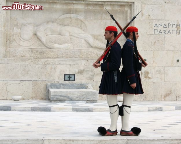 Immagine Il cambio della guardia ad Atene, la capitale della Grecia. Le guardie vegliano il monumento al Milite Ignoto, che si trova in Piazza Syntagma, sottostante al Parlamento Ellenico. I particolari soldati sono  i famosi euzoni, la guardia d'onore greca, chje vestono con le tradizionali camice con gilet, e le fustanelle, dei gonnellini, indossando il fez e delle particolari babbucce (pantofole) dalla punta ricurva  - © Brigida Soriano / Shutterstock.com