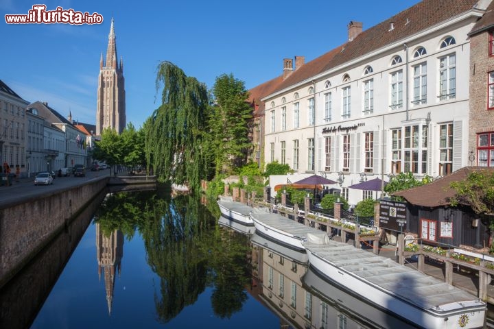 Immagine Panorama sul canale dal ponte Sint Jan Nepomucenus, Bruges - Il campanile della chiesa di Nostra Signora si riflette nelle acque di uno dei canali che attraversano la città di Bruges. Dal ponte Sint Jan Nepomucenus, con gli edifici storici che sembrano voler racchiudere in un abbraccio questo gioiello delle Fiandre e le imbarcazioni ormeggiate ai lati, si può ammirare uno dei panorami più suggestivi di tutto il Belgio  © Renata Sedmakova / Shutterstock.com