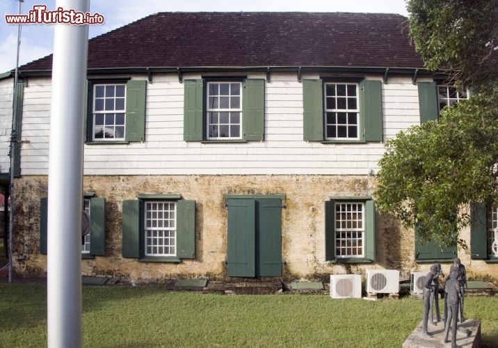 Immagine Casa storica "Vincent Asto Lopes" a Oranjestad, Sint Eustatius (Caraibi Olandesi) - Non è raro che a Sint Eustatius emergano esempi eccellenti dell'edilizia, che ricordano moltissimo la maniera olandese. La località, infatti, appartiene ai Paesi Bassi nella municipalità speciale di Bijzondere Gemeente. Nella fotografia che raffigura la casa storica Vincent Asto Lopes appare evidente la contrapposizione di due materiali: da una parte un legno quasi grezzo, dall'altra nel piano più alto un legno lavorato finemente e verniciato di bianco, il tutto condito da persiane in tinta verde tenue, con i motivi dei vetri piccoli, tipici dell'ordine che tanto piace all'Olanda - © rj lerich / Shutterstock.com