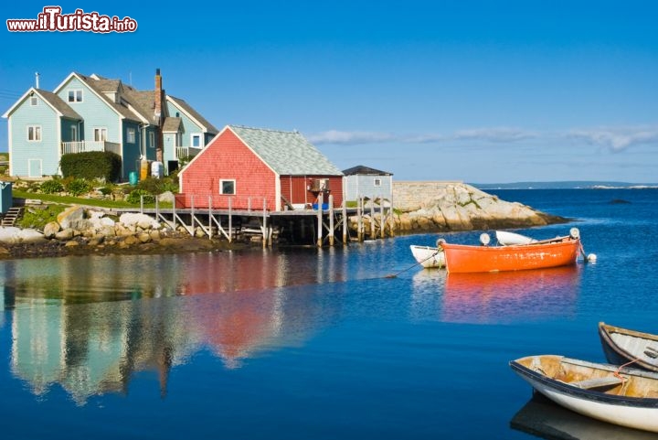Immagine Le case colorate di Peggy's Cove (Nuova Scozia, Canada) si specchiano a testa in giù nel blu acceso del mare. Il legno è il materiale da costruzione per eccellenza, non solo per le abitazioni ma anche per le barche e i moli, e la pesca è da sempre l'attività prediletta - © DOPhoto / Shutterstock.com