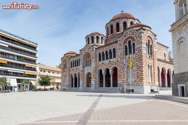 Immagine La Cattedrale di San Nicola a Volos, in Tessaglia, Grecia. Dedicata al patrono della città, Agios Nikolaos, la chiesa è stata completata nel 1934 e ospita, all'interno  del cortile, un bel campanile del 1884 con sculture realizzate da un artista italiano. Sulla piazza di San Nicola si affacciano locali, bar e ristoranti che nelle giornate di sole posizionano all'aperto i loro tavolini - © Lefteris Papaulakis / Shutterstock.com