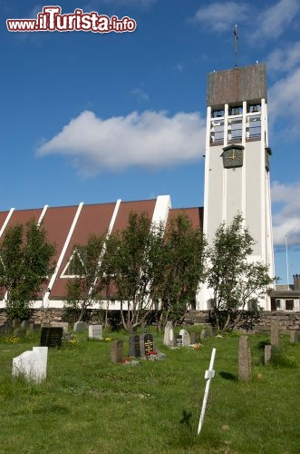 Immagine Cattedrale di Hammerfest, Norvegia - Questa suggestiva località norvegese, la cui economia locale si basa su turismo e pesca, ospita monumenti e palazzi storici fra cui edifici religiosi. A spiccare vi sono la chiesa cattolica di San Michele, terminata nel 1958, che sulla facciata presenta un bel mosaico che raffigura il santo e il drago e una chiesa evangelica di struttura triangolare nota anche per la sua gigantesca vetrata. In questa immagine la cattedrale di Hammerfest immersa nel verde paesaggio rigoglioso della Norvegia © BigRoloImages / Shutterstock.com