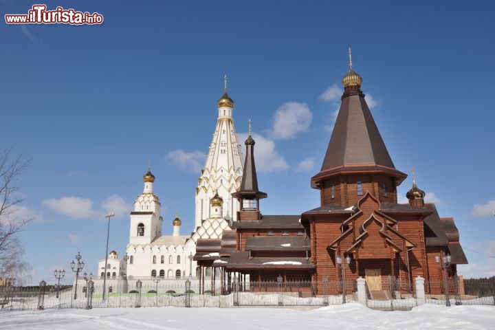 Immagine Minsk, capitale della Bielorussia: una tipica chiesa ortodossa in pietra e in legno e la Chiesa di Tutti i Santi in una giornata di sole - © YuryZap / Shutterstock.com