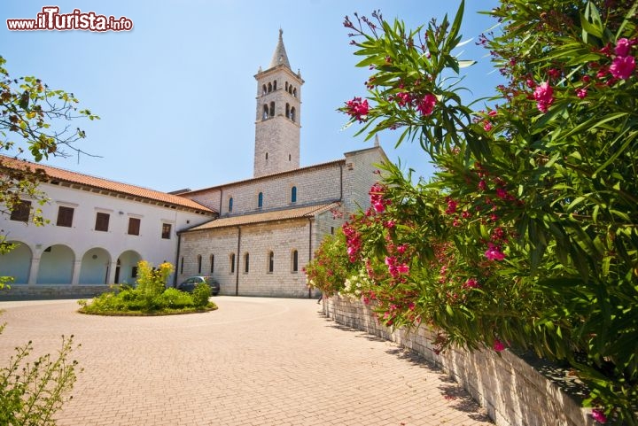 Immagine Chiesa Santa Agnese di Medulin, Istria (Croazia) - Per la forma che si sviluppa in altezza in un monoblocco solo con il campanile e per la struttura che invece nella parte bassa si allunga ma senza alzarsi, ricorda gli edifici ecclesiastici di una periferia di Parigi dell'800. Parallelismo a parte, questo complesso di carattere liturgico si differenzia per il colore e assume la sua piena identità per gli archi. Il bianco, con uno shabby chic decisamente intraprendente, sovrasta tutto il circondario, lasciando anche nelle arcate la sensazione di minimalismo più totale. Un trionfo di semplicità e particolarità architettonica al tempo stesso - © Story / Shutterstock.com