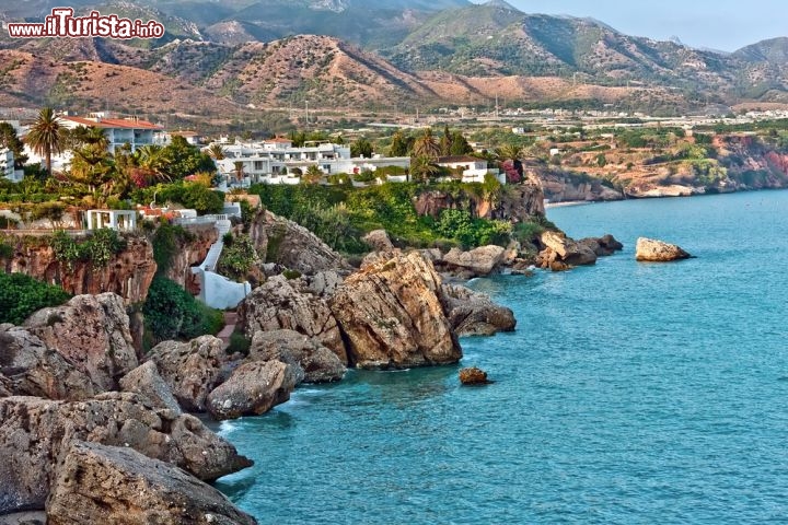 Immagine Costa rocciosa nei pressi di Nerja, Spagna - I dintorni dell'area urbana di Nerja si caratterizzano per spettacolari paesaggi accessibili grazie a sentieri per passeggiate e trekking. In questa immagine un suggestivo tratto costiero di roccia e scogli su cui si affacciano le caratteristiche case intonacate a calce bianca © S.Borisov / Shutterstock.com