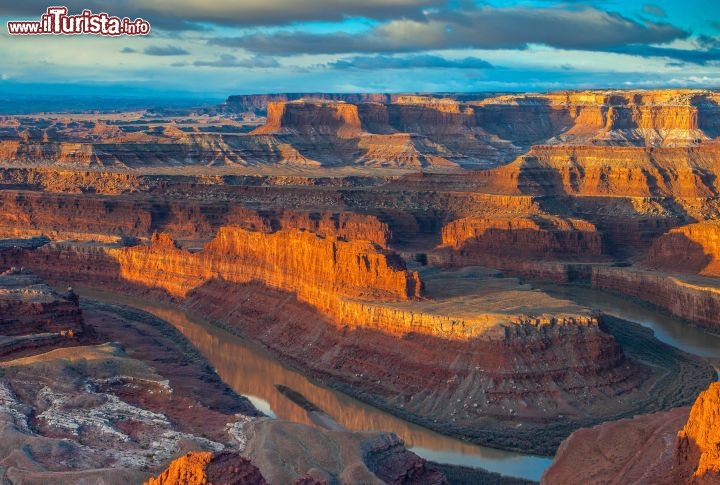 Immagine Al confine con il Canyonlands National Park dello Utah, USA, c'è il Dead Horse Point State Park, uno spettacolare "promontorio" roccioso lambito dalle acque del Colorado, immortalato da pellicole storiche come Thelma e Louise. Il nome è dovuto all'utilizzo che i cowboy ne facevano, nell'Ottocento, come recinto naturale per i cavalli. Nell'immagine le luci dell'alba accentuano il contrasto tra il rosso della roccia e l'azzurro del cielo - © Doug Meek / Shutterstock.com