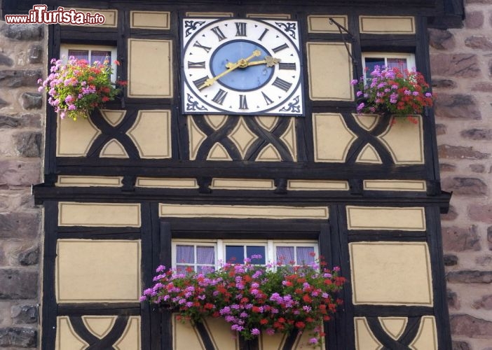 Immagine Dettaglio del Dolder a Riquewihr, Francia - Anche la bella torre dell'orologio di Riquewihr non poteva che presentarsi con le caratteristiche decorazioni in legno tipiche dell'architettura di molti paesi del centro Europa. Ad abbellire l'orologio del Dolder non mancano fiori variopinti che ne impreziosiscono la facciata © Pack-Shot / Shutterstock.com