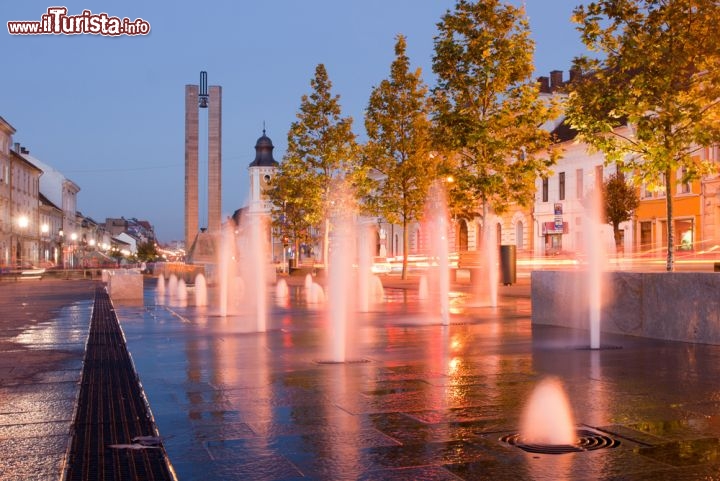 Immagine Fontana in piazza Unirii, Cluj Napoca - Unirii Square, la grande piazza di Cluj, ospita una suggestiva fontana che da terra spruzza getti di acqua verso l'alto. Con il tramonto il gioco di acqua e luci diventa ancora più emozionante © alex_bendea / Shutterstock.com