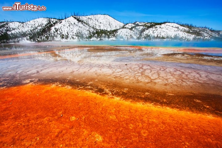 Immagine Grand Prismatic Spring nel Midway Gayser Basin dello Yellowstone National Park (USA): sullo sfondo le montagne con la neve. Il parco possiede un'altezza media di 1700 metri e quindi in inverno nevica in modo abbondante - © Katrina Leigh / Shutterstock.com