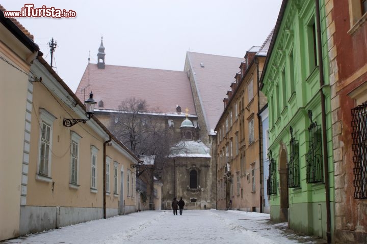 Immagine Kapitulska Street con la neve, Bratislava - Le facciate variopinte degli edifici che si affacciano su questa storica via di Bratislava accompagnano alla scoperta di un suggestivo scorcio della città slovacca. Anche in questa immagine il centro cittadino è fotografato dopo una nevicata - © Renata Sedmakova / Shutterstock.com