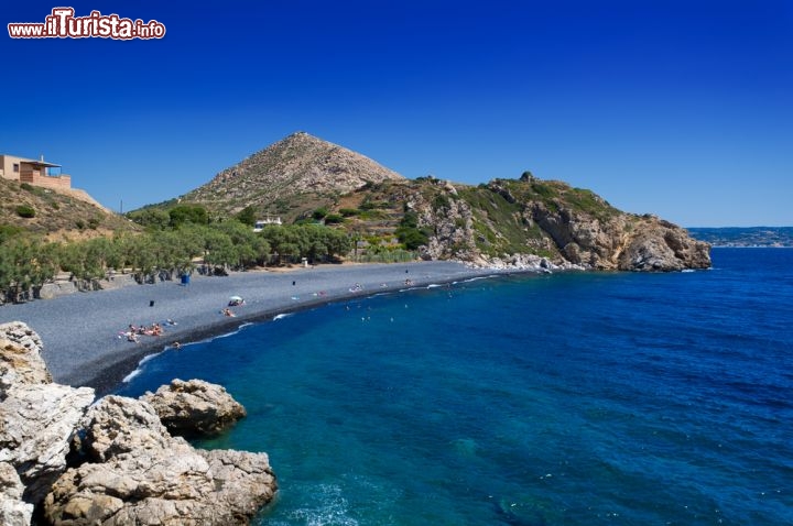 Immagine La spiaggia di Mavra Bolia sull'isola di Chios (Grecia nord-orientale) è meglio nota come "spiaggia dei ciottoli neri", per i suoi sassi scuri generati dall'attività vulcanica che in passato si verificava in questa zona della Grecia. Si tratta in realtà di tre baie vicine tra loro, accomunate da uno splendido mare blu intenso e da un'imponente cornice montuosa - © Steliost / Shutterstock.com
