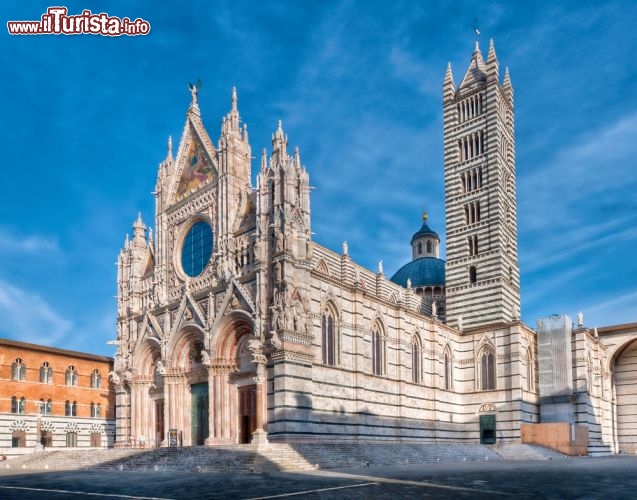 Immagine La spledida Cattedrale di Siena, dedicata a Santa Maria Assunta, fotografata al mattino presto con un cielo terso alle spalle. La facciata è riccamente decorata, realizzata in marmo bianco con dettagli in rosso di Siena e serpentino di Prato - © Michael Avory / Shutterstock.com