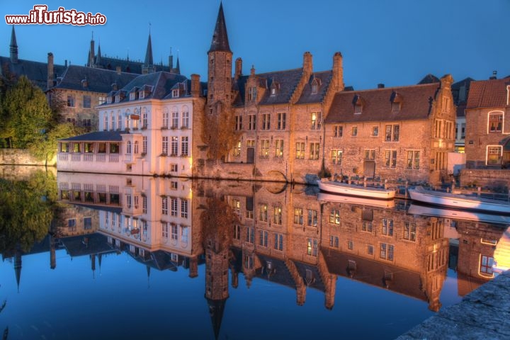 Immagine Magia notturna del Rozenhoedkaai, Bruges - Costeggiati da dimore fiamminghe e da antichi magazzini, testimonianza che un tempo le vie d'acqua che attraversano Bruges venivano utilizzate per trasportare le merci dal mare sino nel cuore della città, i canali sono una delle caratteristiche di questa località delle Fiandre. Fra i panorami più fotografati c'è quello che si può ammirare dal Rozenhoedkaai qui ritratto al calar del sole con i palazzi che si riflettono imponenti e maestosi nelle acque © Rob van Esch / Shutterstock.com